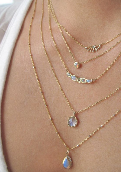 5 14k yellow gold opal necklaces on woman's neck.