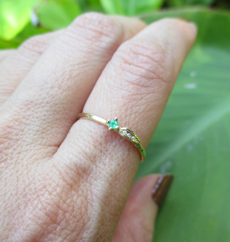 Sprout emerald ring three white round brilliant accent diamonds on hand.