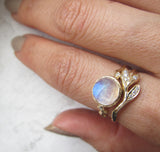 Sway Ring with White Round Brilliant Diamonds next to Opal Ring on Woman's Hand.