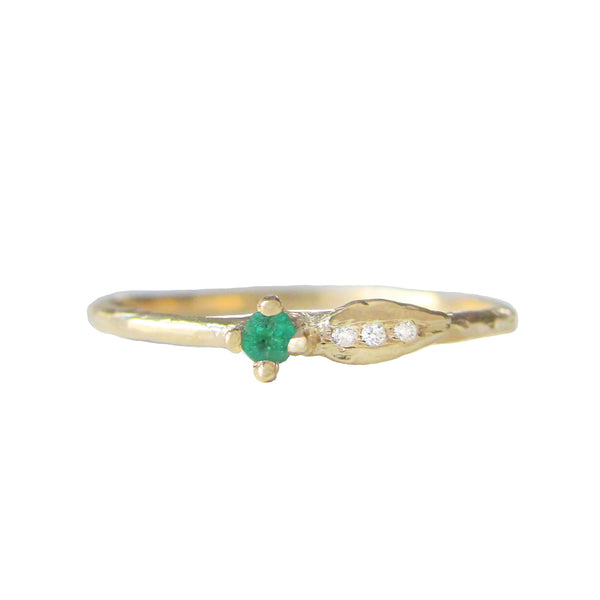 Sprout emerald ring with three white round brilliant accent diamonds.