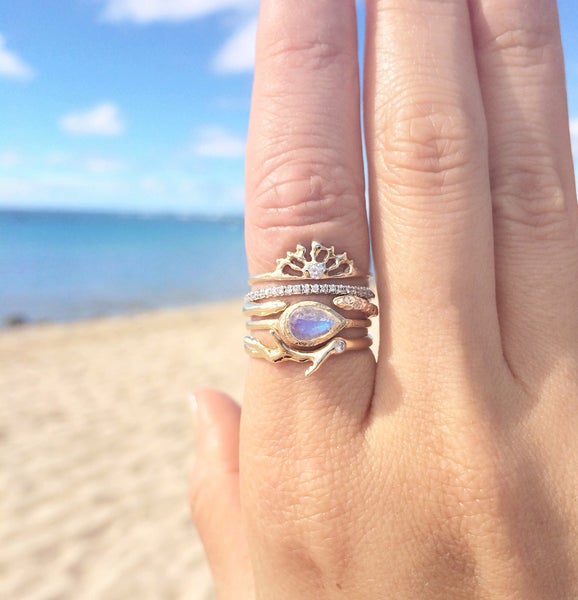 Handcrafted opal rings on model's hand by the beach