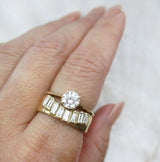 14K gold ring with baguette diamonds on a finger paired with a diamond solitaire ring