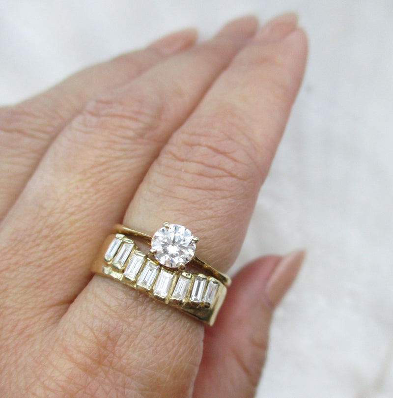 14K gold ring with baguette diamonds on a finger paired with a diamond solitaire ring