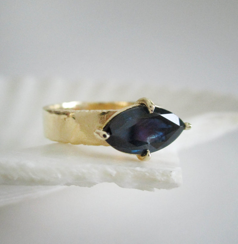 14K yellow gold 5mm ring with 4 prong marquis sapphire center on a white background