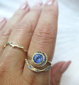 14K gold stacking rings with blue sapphires on a hand against a white background