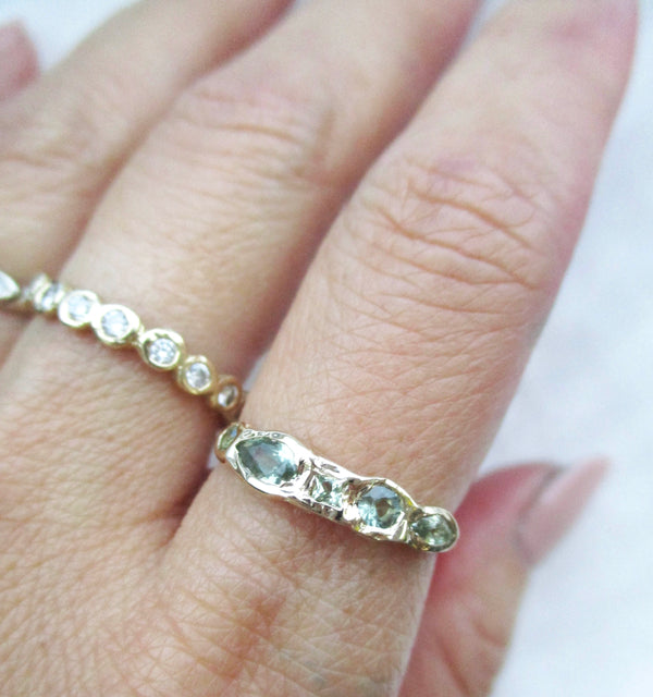 14K gold green sapphire ring on the hand against a white background