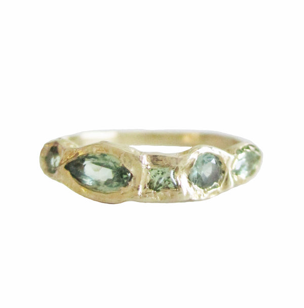 14K gold ring with green sapphires against a white background 