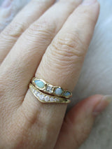 14K yellow gold opal and aquamarine ring stacked with a curved diamond ring on the hand