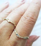 Gold ring with blue stones on a finger against a white background