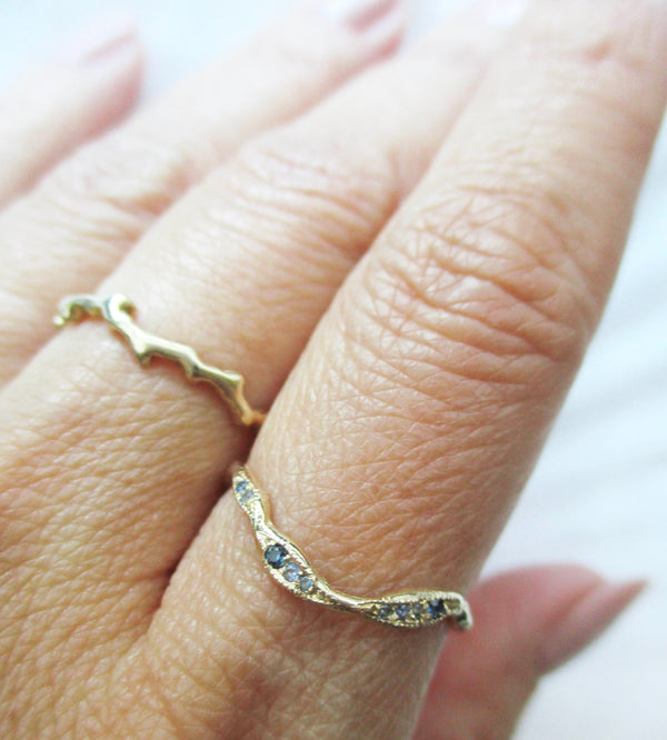 Gold ring with blue stones on a finger against a white background