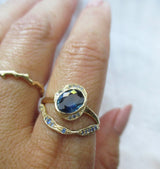 14K gold stacking rings with blue sapphires on a hand against a white background