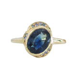 14K gold ring with an oval blue sapphire and halo on a white background
