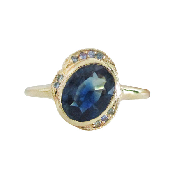 14K gold ring with an oval blue sapphire and halo on a white background