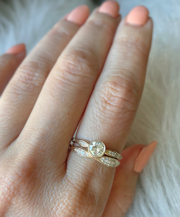 14K gold ring with round diamonds on a hand against a white background 