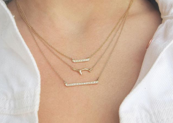 3 Yellow gold necklaces with diamonds on woman's neck.