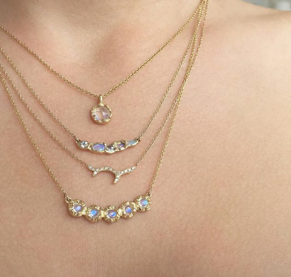 4 14k yellow gold opal necklaces on woman's neck.