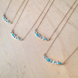 4 Turquoise and blue topaz yellow gold necklaces on table.