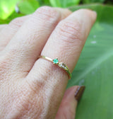 Sprout emerald ring three white round brilliant accent diamonds on hand.