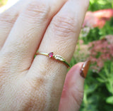 Sprout ruby ring three white round brilliant accent diamonds on hand.