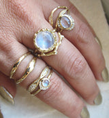 Set of 14k yellow gold rings on woman's hand, including Nesting Moonstone Ring.