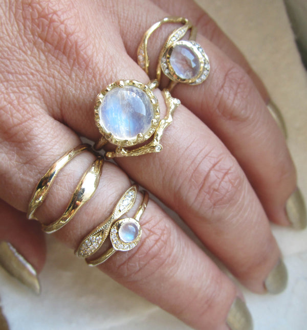 Set of 14k yellow gold rings on woman's hand, including Nesting Moonstone Ring.