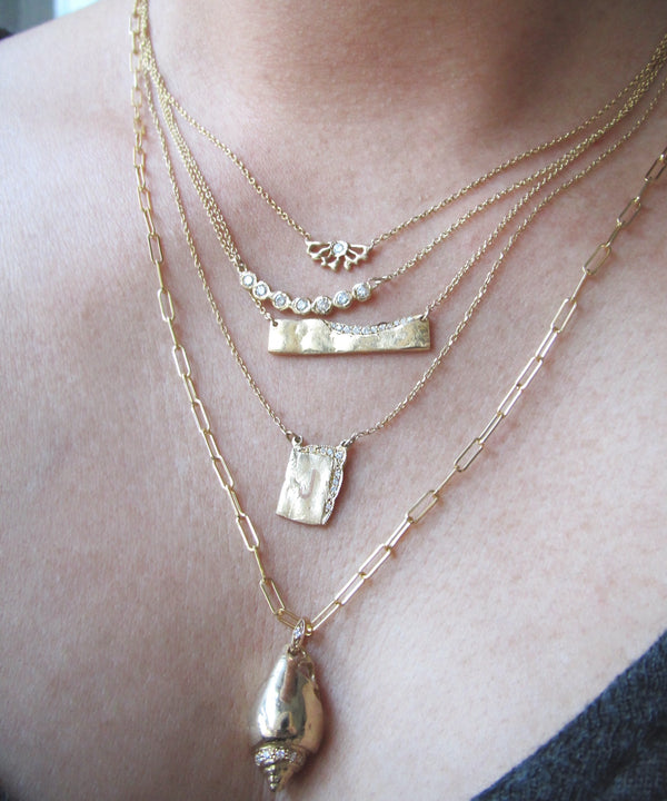 Queen's conch necklace with a set of other 4 gold necklaces.