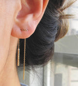 Scenic gold ear threader weaved through multiple piercings.