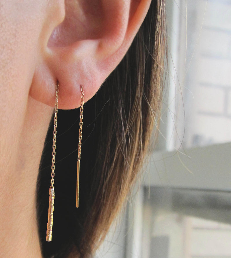 Scenic gold ear threader weaved through two piercings.