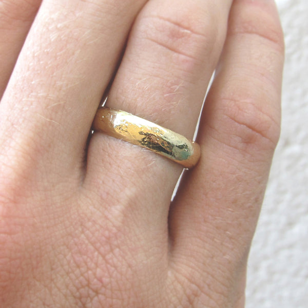 Gold half round band on woman's hand. 