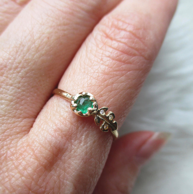 Floret Emerald Ring with three white diamonds on hand
