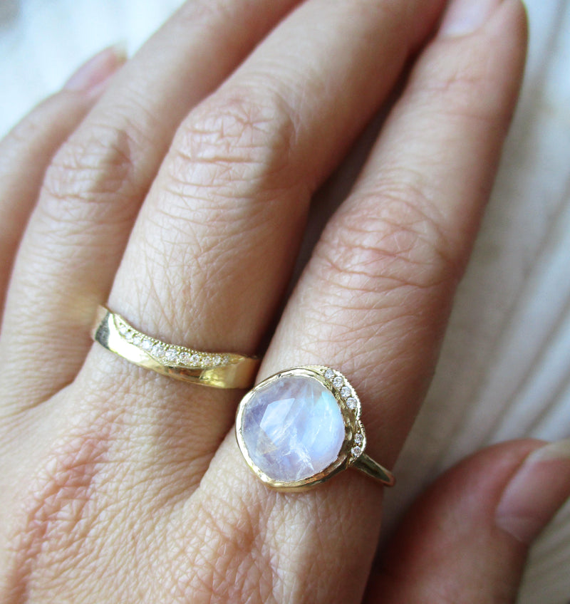 Middle cove moonstone ring with a strip of white round brilliant diamonds on hand.