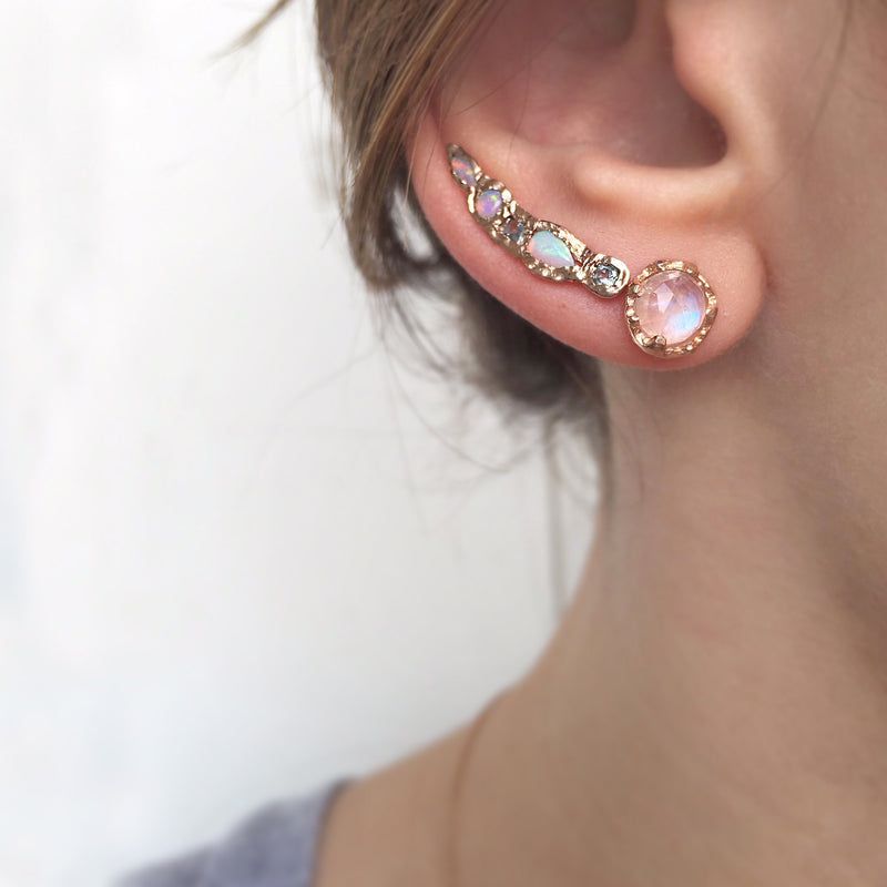 Opal and aquamarine ear crawlers on woman's ear.