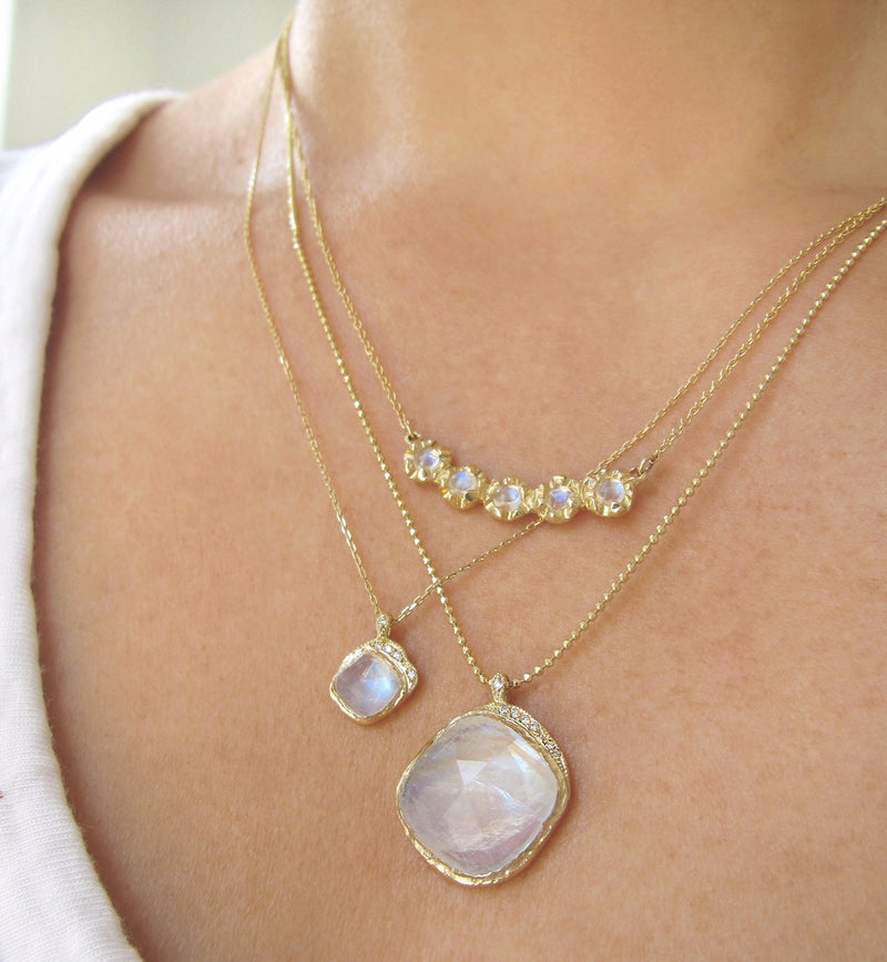 Mini cove moonstone necklace with white round brilliant diamonds on woman's neck.