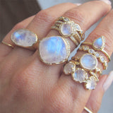 Yellow gold moonstone rings on woman's hand.