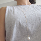 14K gold necklace with pearl on woman's neck.