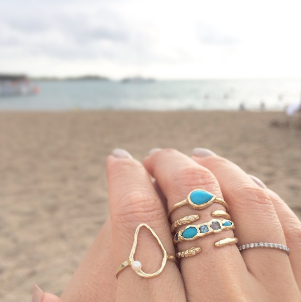 Yellow gold Oysterette Ring with Pearl on woman's hand by the beach.