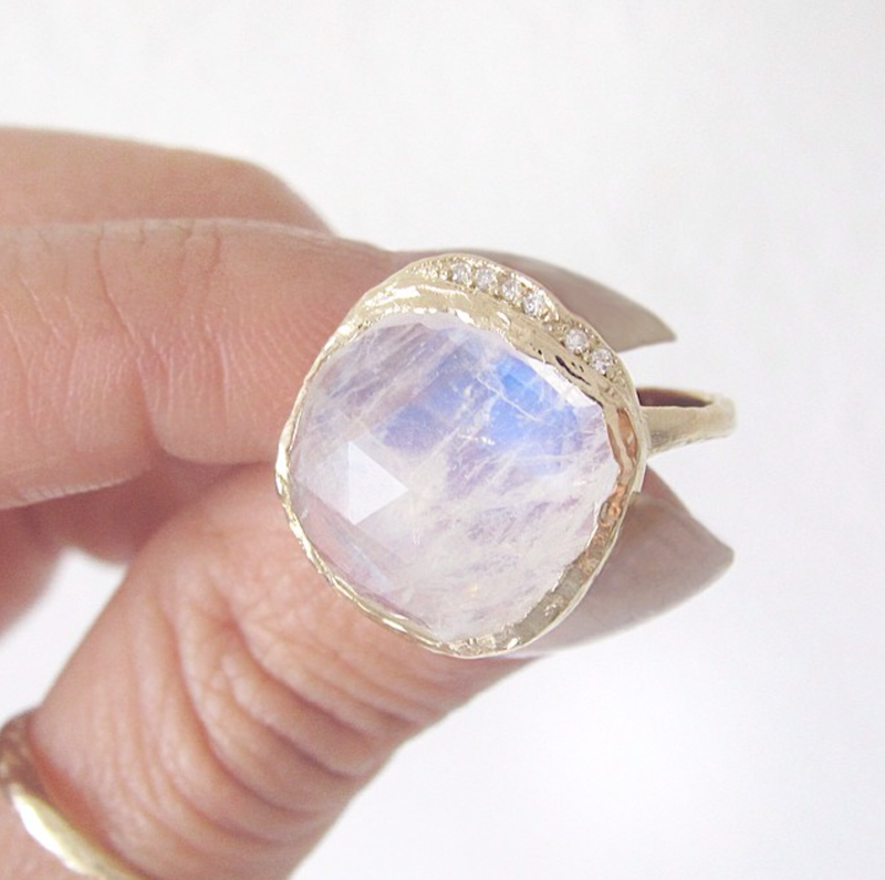 Moonstone Yellow Gold Ring with white round brilliant diamonds between woman's finger.