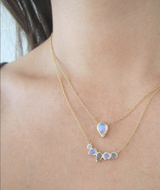 Grey diamond, labradorite and rainbow moonstone gold necklace on woman's neck.