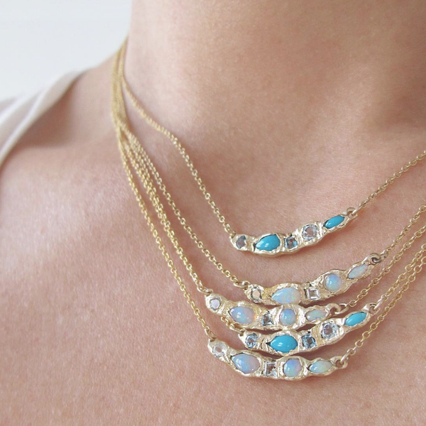 4 Turquoise and blue topaz yellow gold necklaces on woman's neck. 
