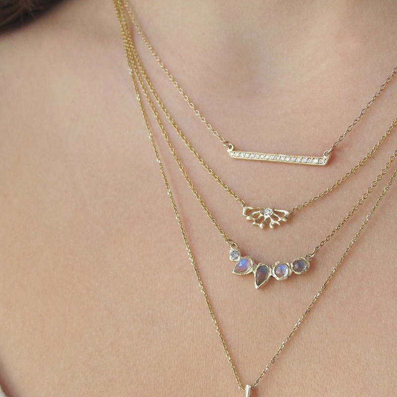 4 Yellow gold necklaces with diamonds on woman's neck.