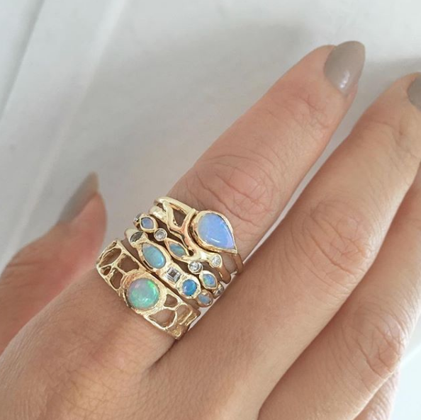 Gold Opal Rings on woman's index finger. 