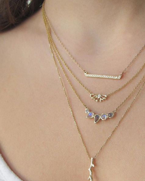 4 Gold necklaces with diamonds on woman's neck.