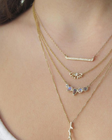 Single Grey diamond, labradorite and rainbow moonstone gold necklace on woman's neck.